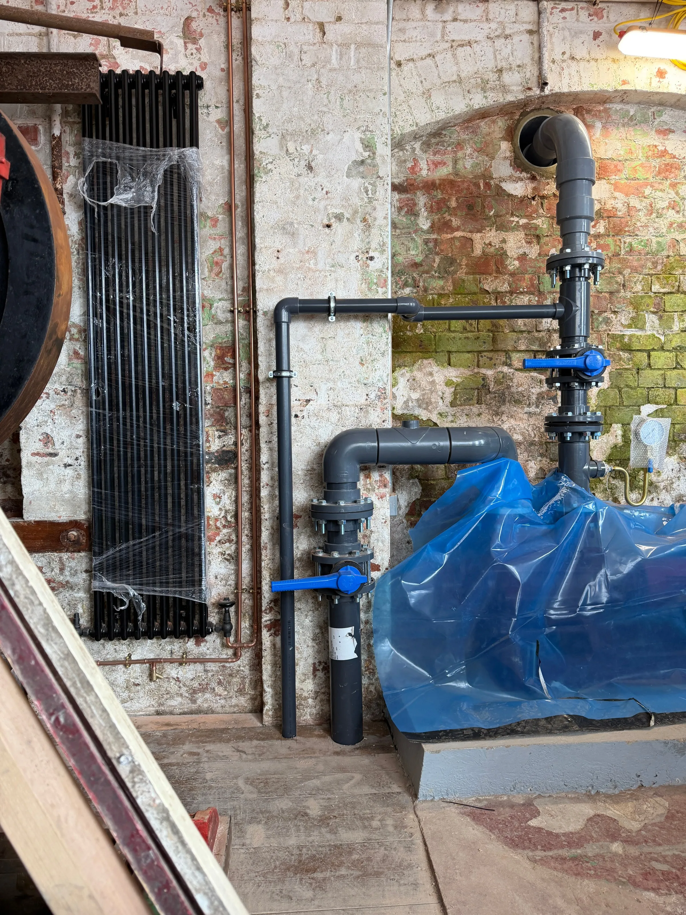 Pipework and cast-iron radiator inside the Leas Lift engine house, mid-restoration