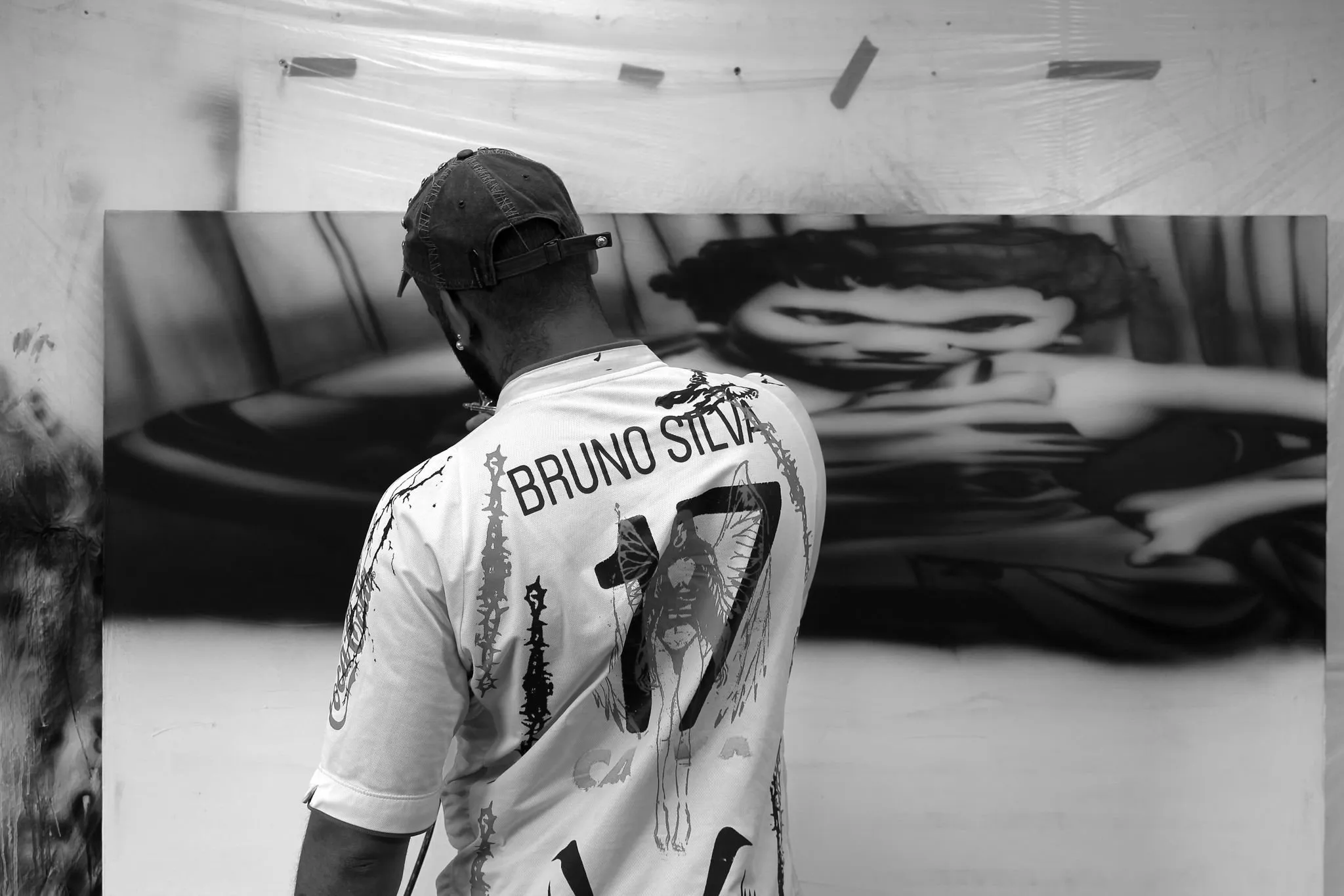 Mattia Guarnera-MacCarthy airbrushing the reclining-figure painting in his studio, seen from behind