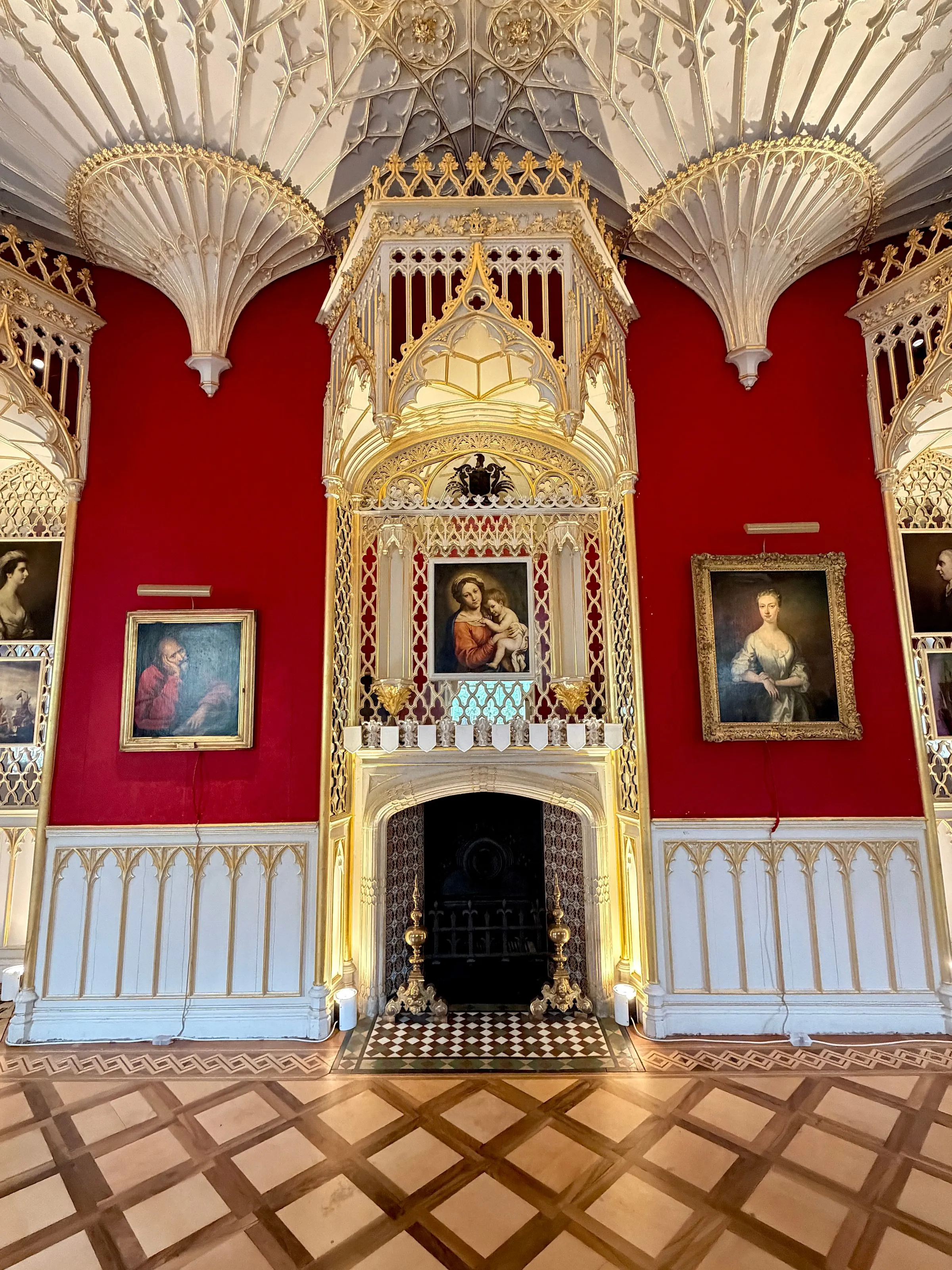 The Gallery chimneypiece, a white and gilt Gothic canopy between fan vaults, flanked by portraits on crimson walls